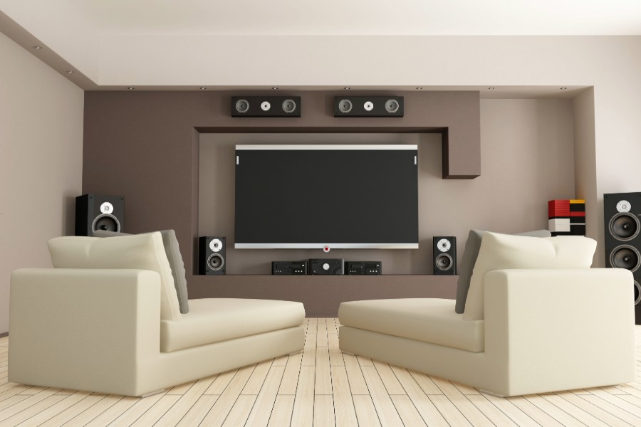 Two chairs facing a large screen in a modern home theater featuring speakers.