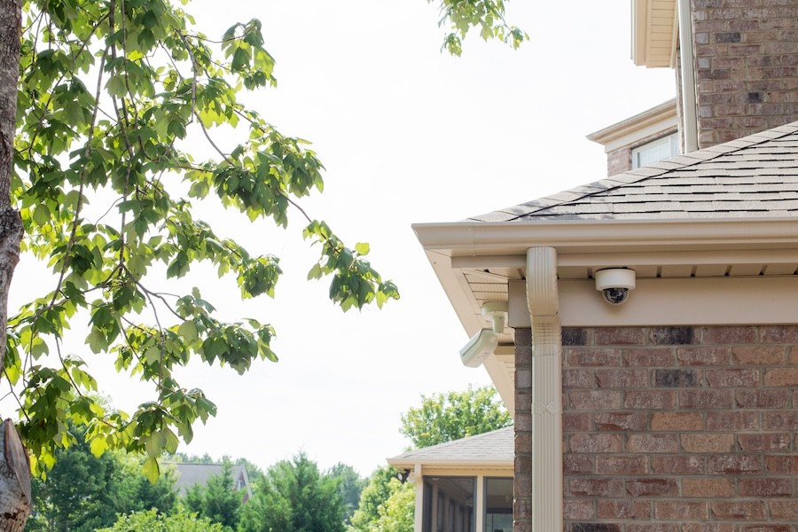 A security camera mounted on a house keeps an eye on outdoor activities.