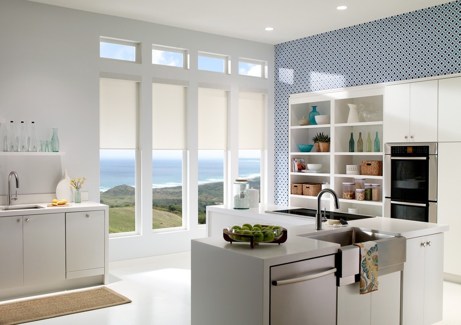 Diffuse sunlight entering a kitchen through windows with shades partially drawn overlooking the ocean.