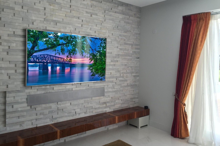 Customized James Loudspeaker installed in brick wall home theater under large screen TV.