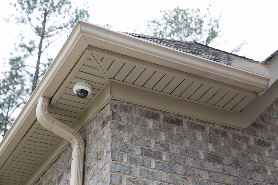 Photo of a dome home security camera installed near the gutter of a home.